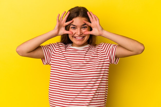 Young caucasian woman isolated on yellow background keeping eyes opened to find a success opportunity.