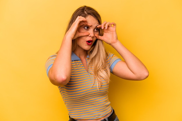 Young caucasian woman isolated on yellow background keeping eyes opened to find a success opportunity