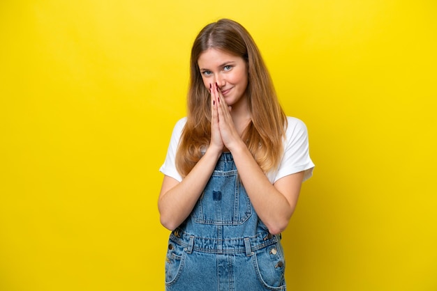 Young caucasian woman isolated on yellow background keeps palm together Person asks for something