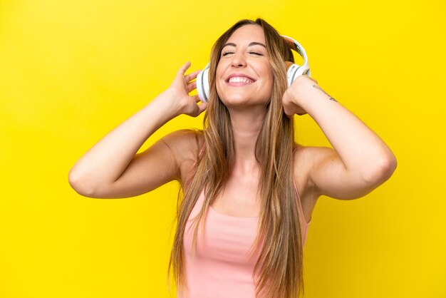 Young caucasian woman isolated on yellow background listening music and singing