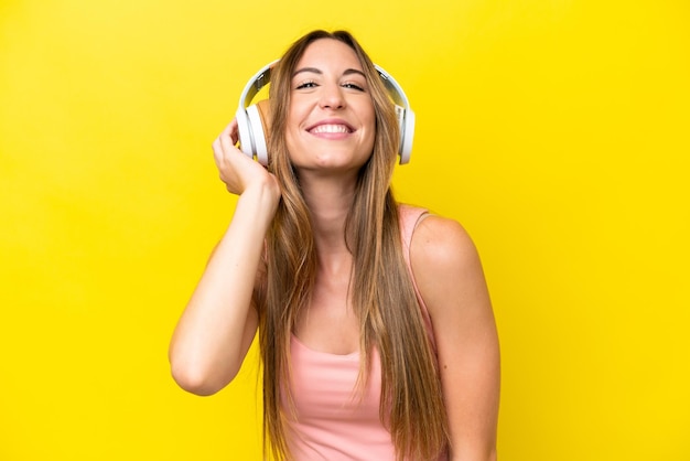 Giovane donna caucasica isolata sulla musica d'ascolto del fondo giallo