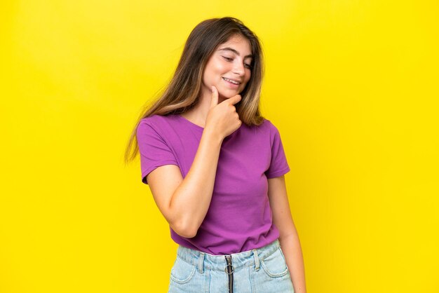 Young caucasian woman isolated on yellow background looking to the side and smiling