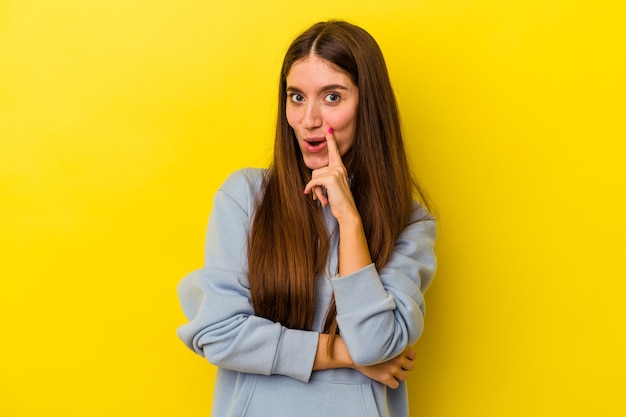 Young caucasian woman isolated on yellow background looking sideways with doubtful and skeptical expression.