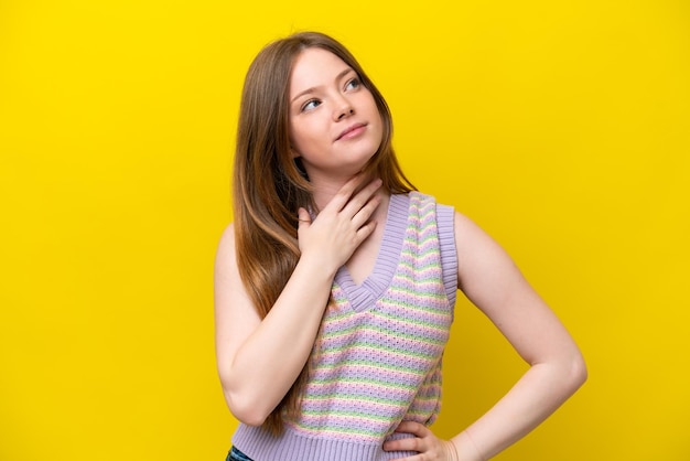 Young caucasian woman isolated on yellow background looking up while smiling