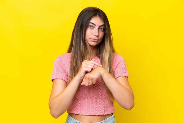 Foto giovane donna caucasica isolata su sfondo giallo che fa il gesto di essere in ritardo