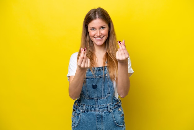 Young caucasian woman isolated on yellow background making money gesture