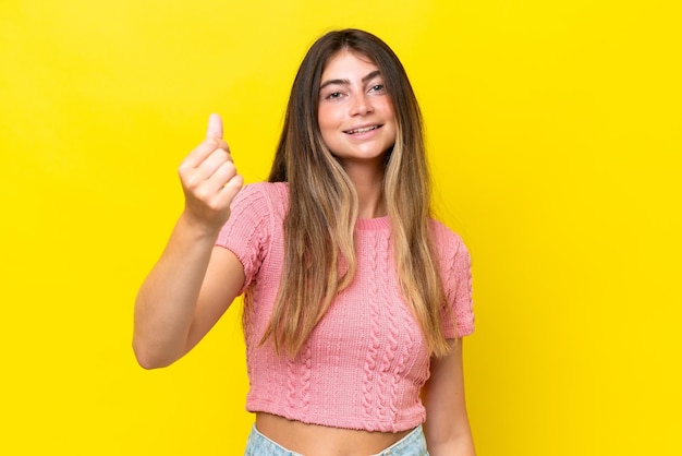 Young caucasian woman isolated on yellow background making money gesture