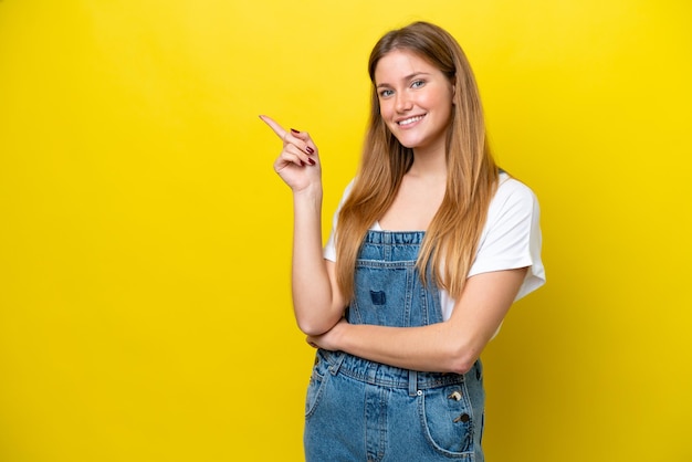 Young caucasian woman isolated on yellow background pointing finger to the side