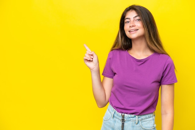 Young caucasian woman isolated on yellow background pointing finger to the side