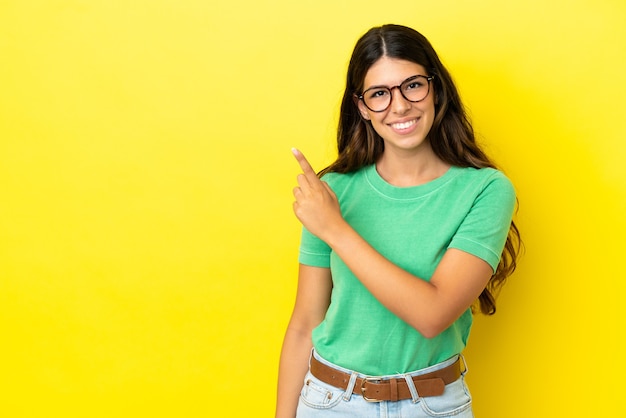 Young caucasian woman isolated on yellow background pointing to the side to present a product