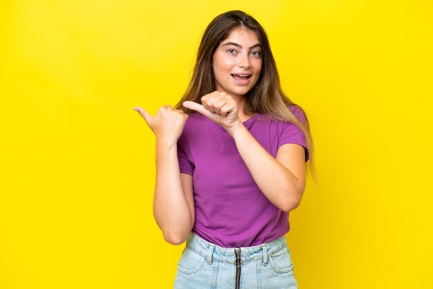 Young caucasian woman isolated on yellow background pointing to the side to present a product