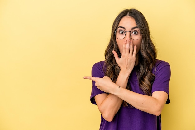 Foto giovane donna caucasica isolata su sfondo giallo che indica il lato