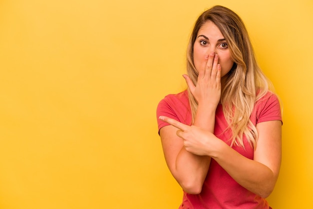 Young caucasian woman isolated on yellow background pointing to the side