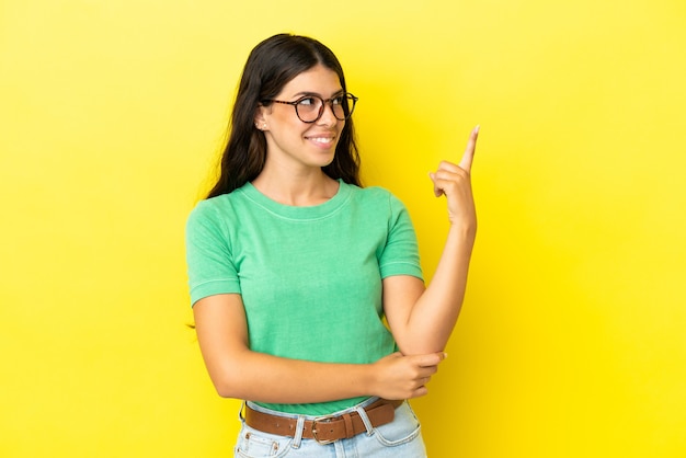 Young caucasian woman isolated on yellow background pointing up a great idea