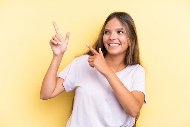 Young caucasian woman isolated on yellow background pointing with the index finger a great idea