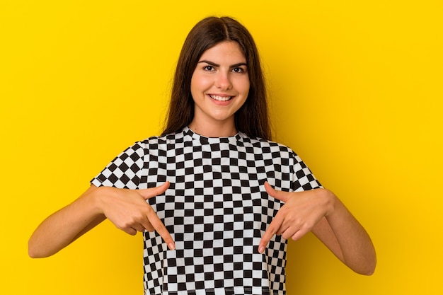 Young caucasian woman isolated on yellow background points down with fingers, positive feeling.