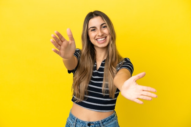 Young caucasian woman isolated on yellow background presenting and inviting to come with hand