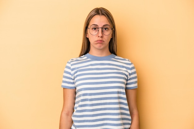 Young caucasian woman isolated on yellow background sad, serious face, feeling miserable and displeased.