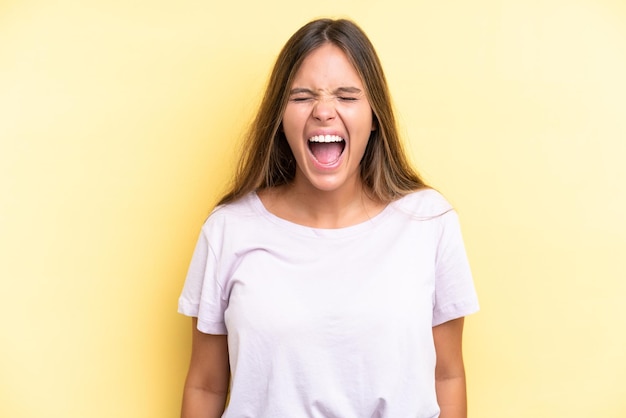 Young caucasian woman isolated on yellow background shouting to the front with mouth wide open