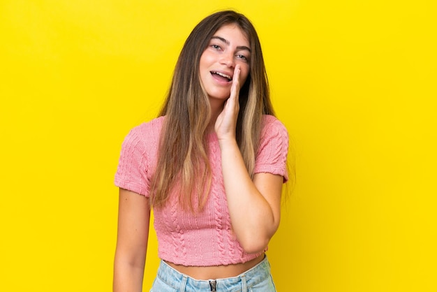 Young caucasian woman isolated on yellow background shouting with mouth wide open