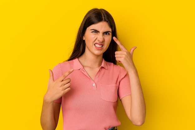 Young caucasian woman isolated on yellow background showing a disappointment gesture with forefinger.