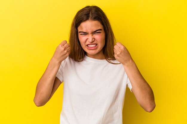 Photo young caucasian woman isolated on yellow background showing fist to camera, aggressive facial expression.