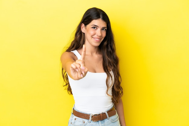 Young caucasian woman isolated on yellow background showing and lifting a finger