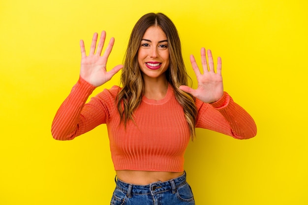 Young caucasian woman isolated on yellow background showing number ten with hands.