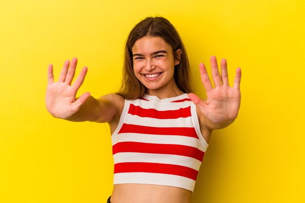 Young caucasian woman isolated on yellow background showing number ten with hands.