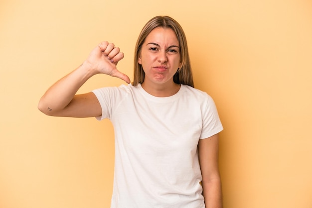 Young caucasian woman isolated on yellow background showing thumb down and expressing dislike.