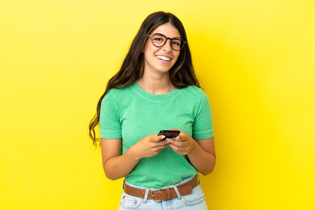 Young caucasian woman isolated on yellow background surprised and sending a message