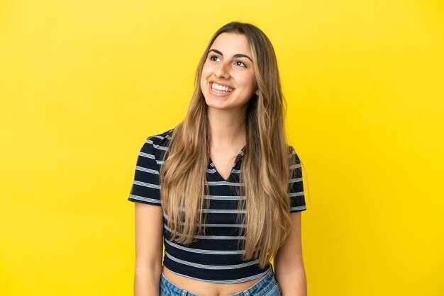 Young caucasian woman isolated on yellow background thinking an idea while looking up