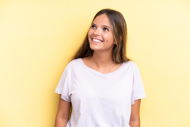 Young caucasian woman isolated on yellow background thinking an idea while looking up