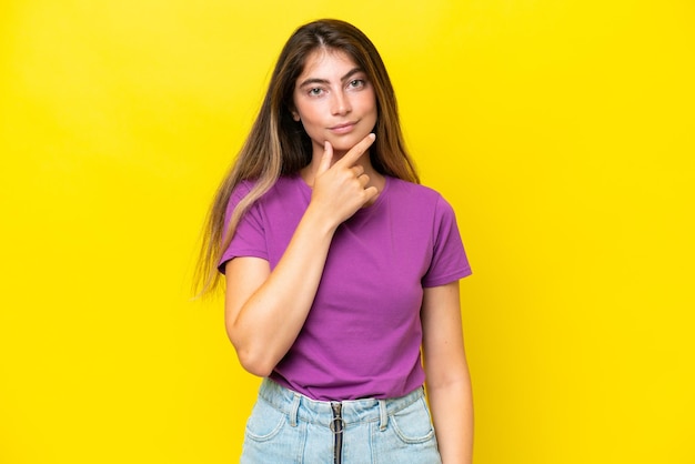 Young caucasian woman isolated on yellow background thinking