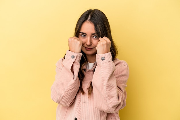 Young caucasian woman isolated on yellow background throwing a punch, anger, fighting due to an argument, boxing.