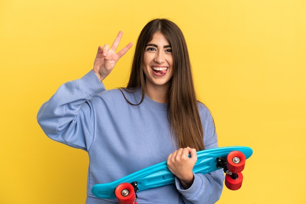 Young caucasian woman isolated on yellow background with a skate with happy expression