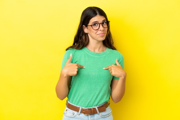 Young caucasian woman isolated on yellow background with surprise facial expression