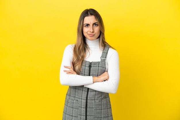 Young caucasian woman isolated on yellow background with unhappy expression