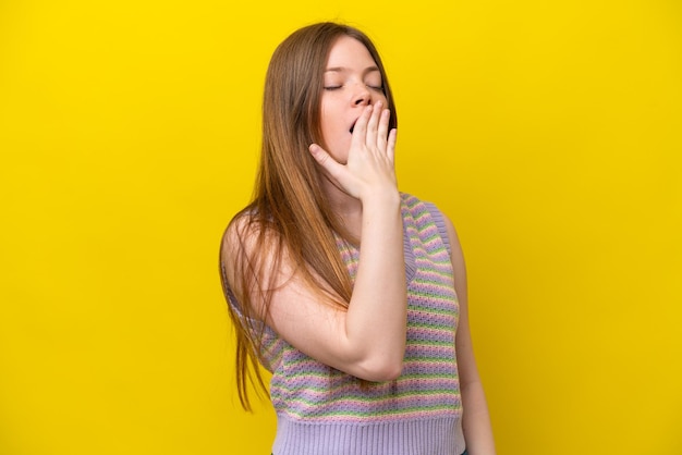 Photo young caucasian woman isolated on yellow background yawning and covering wide open mouth with hand