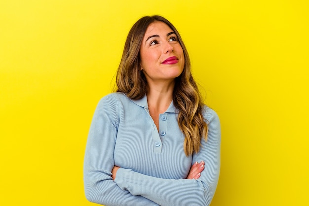 Young caucasian woman isolated on yellow dreaming of achieving goals and purposes