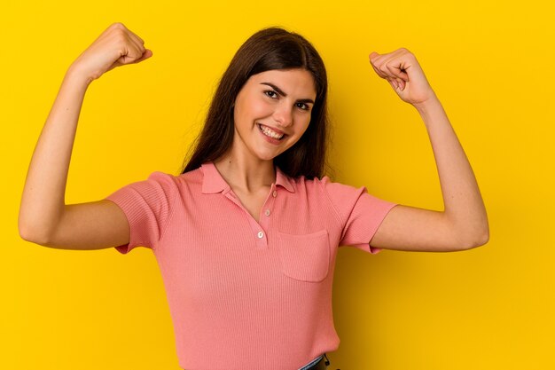 Young caucasian woman isolated on yellow wall cheering carefree and excited. Victory concept.