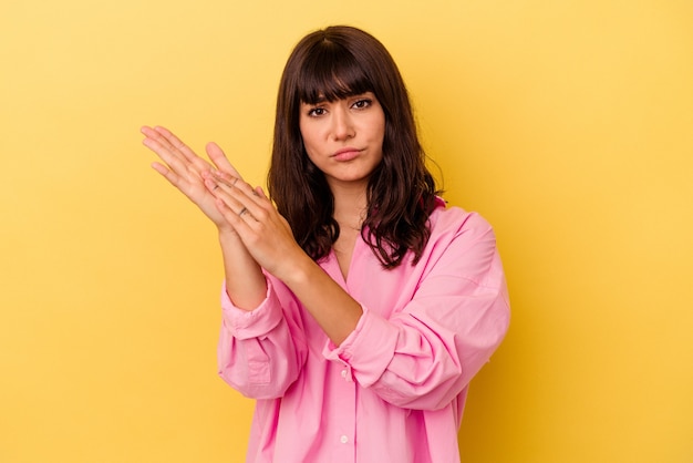 Young caucasian woman isolated on yellow wall feeling energetic and comfortable, rubbing hands confident