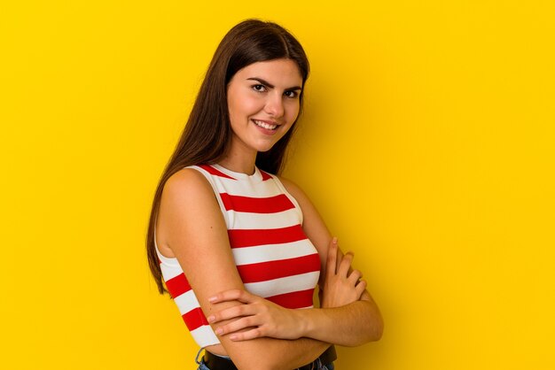 Young caucasian woman isolated on yellow wall laughing and having fun.