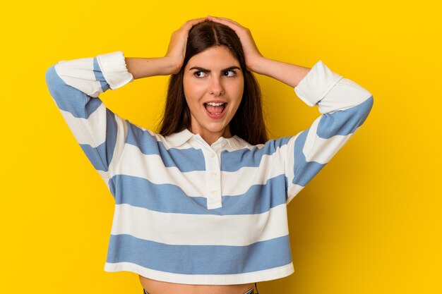 Young caucasian woman isolated on yellow wall screaming, very excited, passionate, satisfied with something.