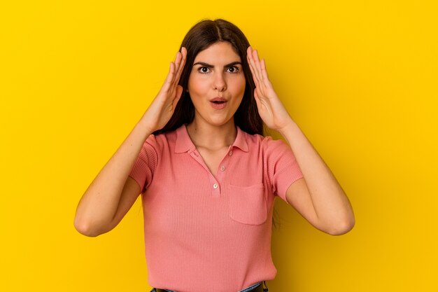 Young caucasian woman isolated on yellow wall surprised and shocked