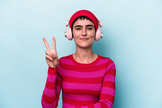 Young caucasian woman listening to music isolated on background showing number two with fingers.