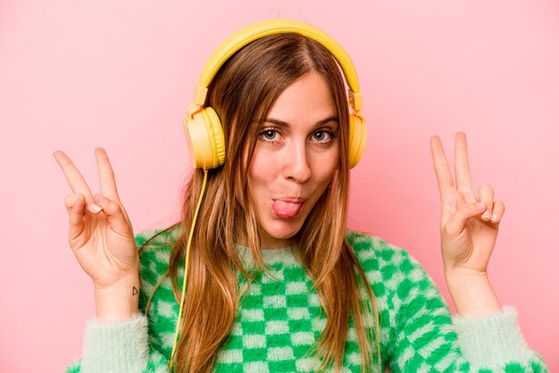 Young caucasian woman listening to music isolated on pink background