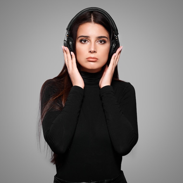 Young caucasian woman listening music in wireless headhones on isolated background