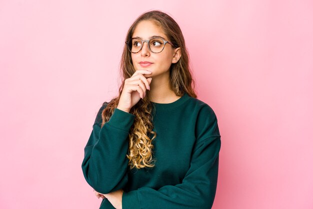 Young caucasian woman looking sideways with doubtful and skeptical expression.