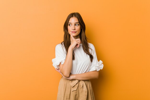 Young caucasian woman looking sideways with doubtful and skeptical expression